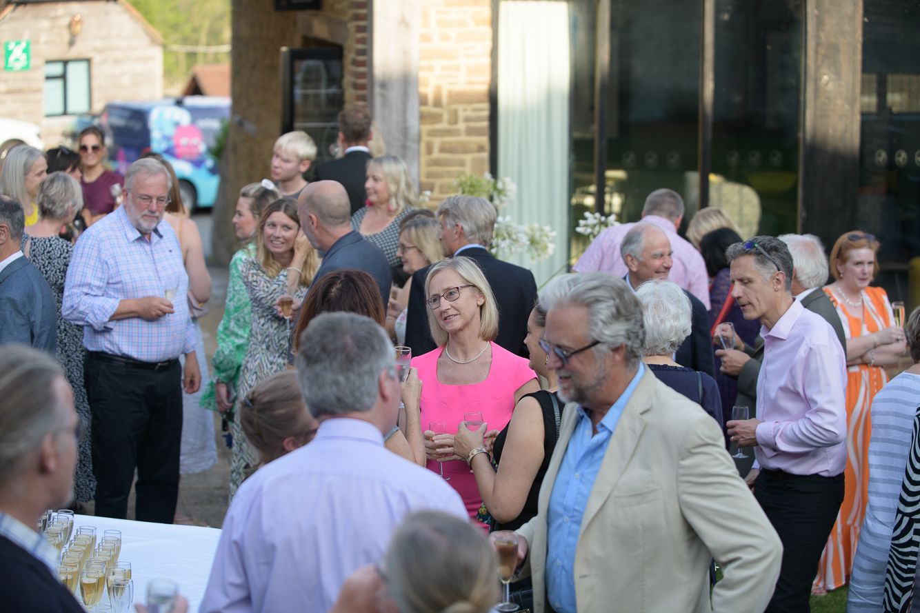 Members talking over drinks in a courtyard at the Surrey Hills Enterprises summer party
