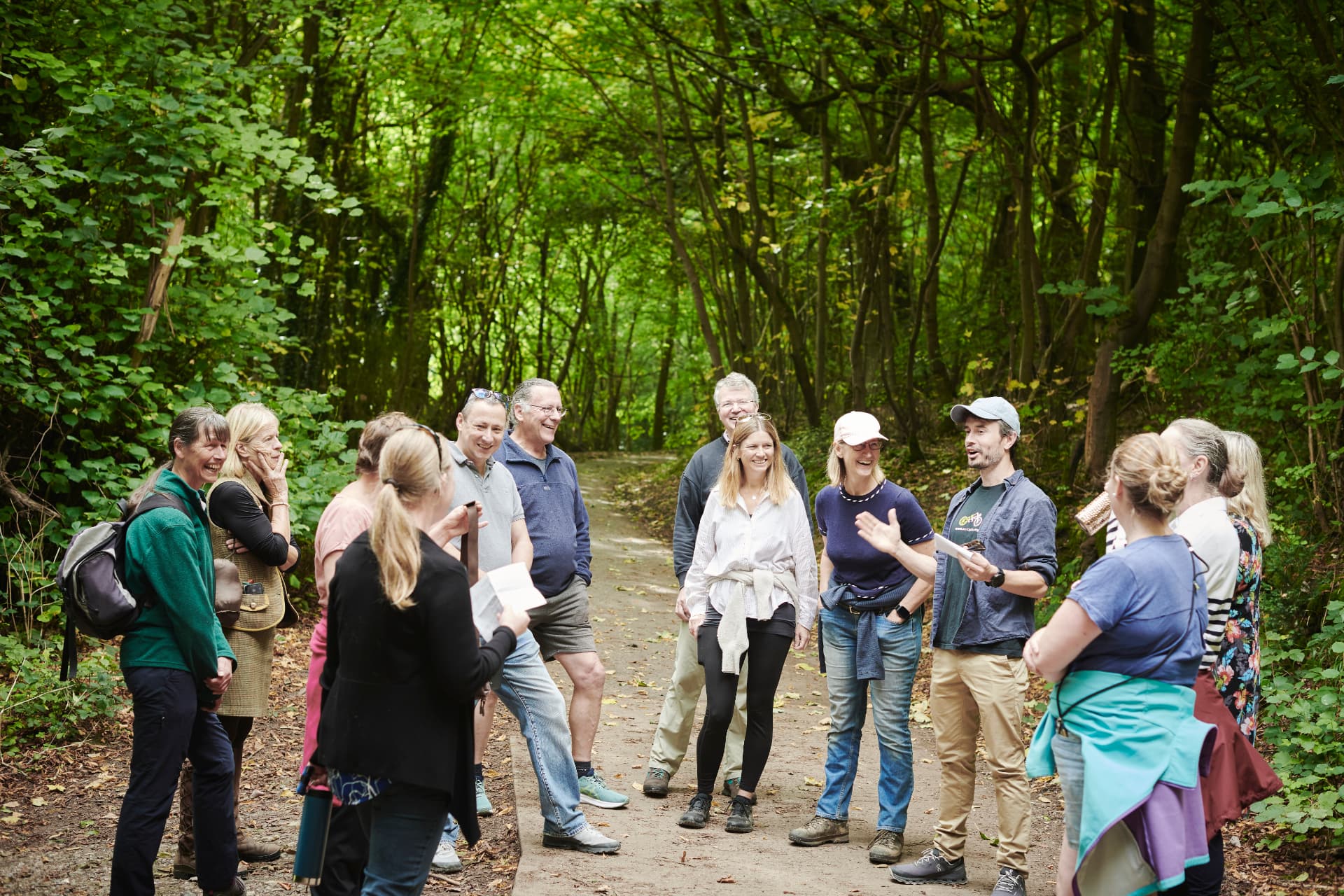Members laughing together on a woodland track during a walking networking session