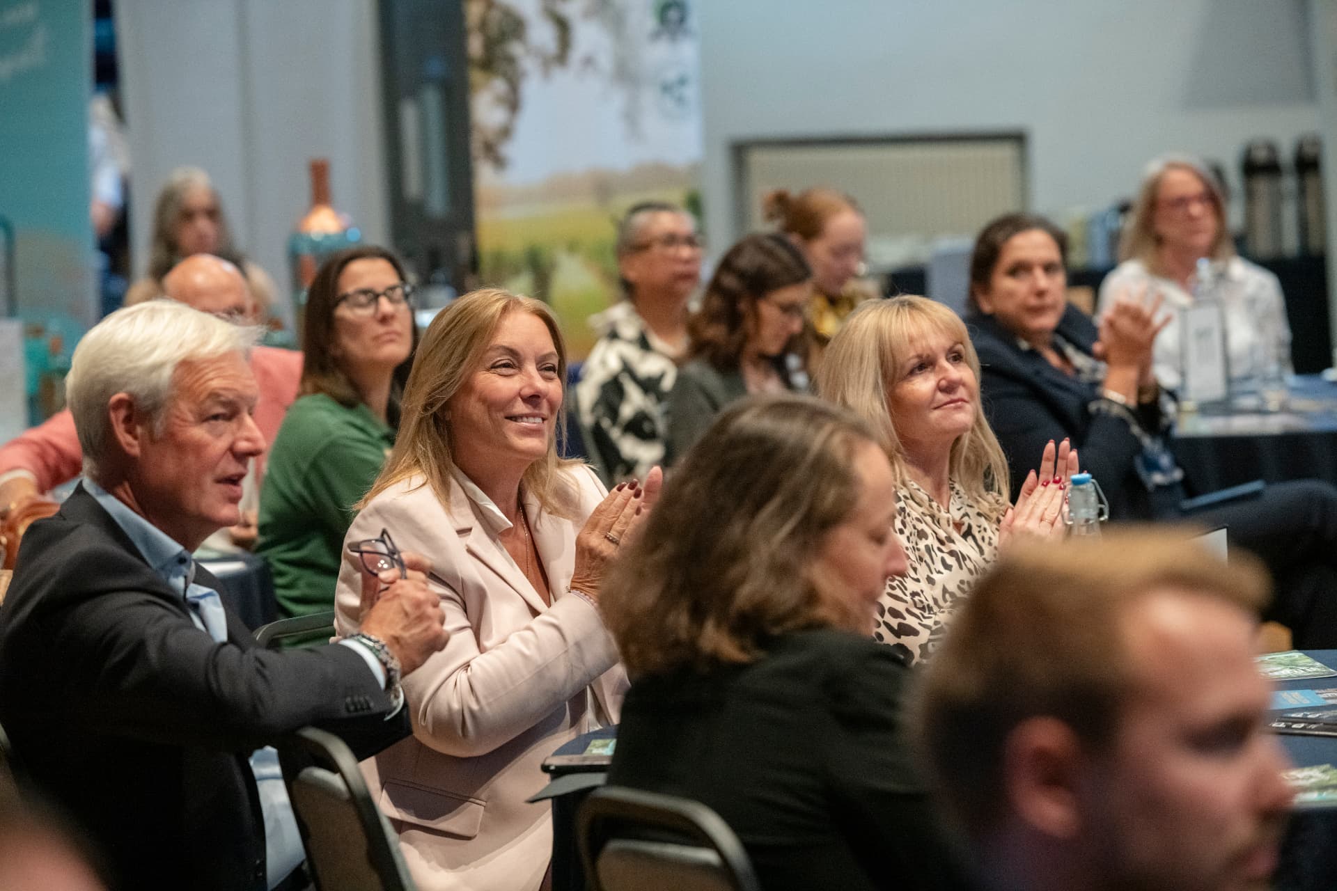 Members smiling and applauding together during an event