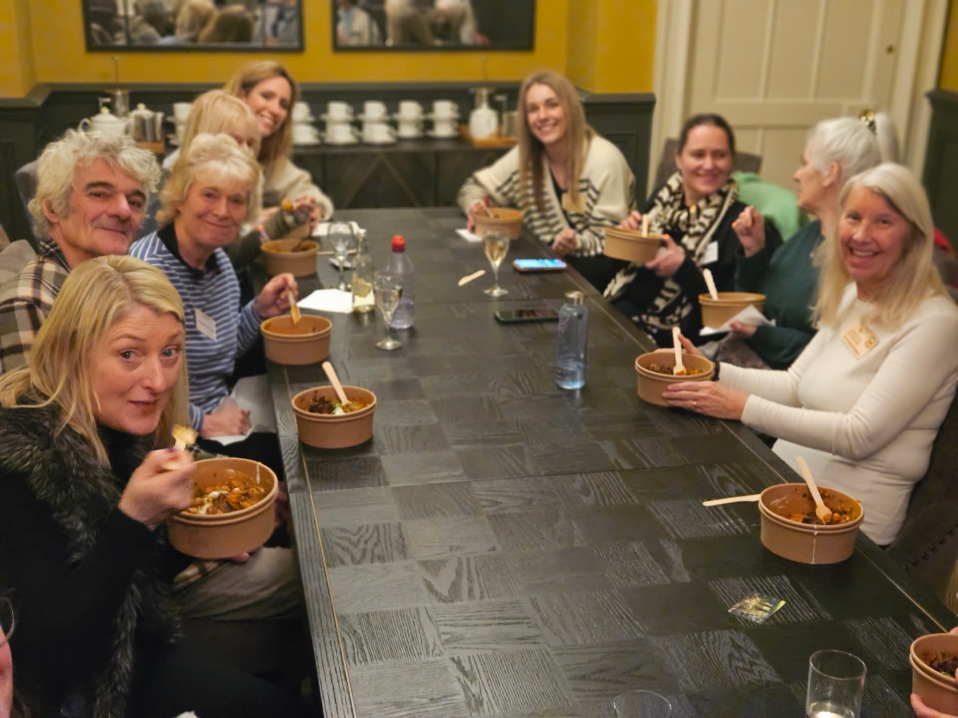 Members smiling around a long table over a casual supper at Harry Edwards